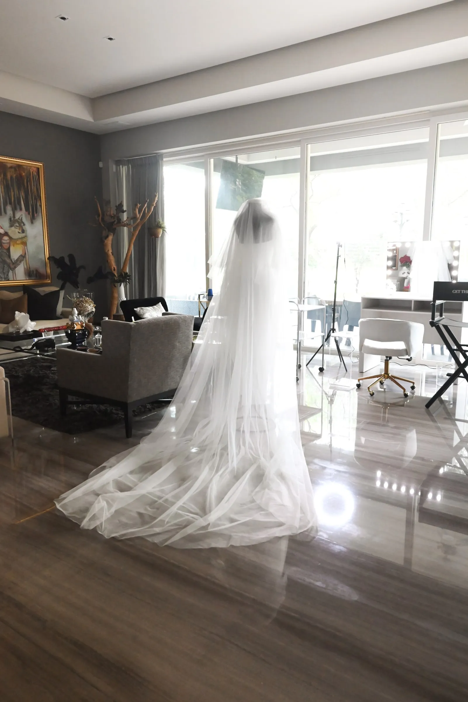 Vestido de novia con el velo extendido sobre el piso y el set montado al fondo