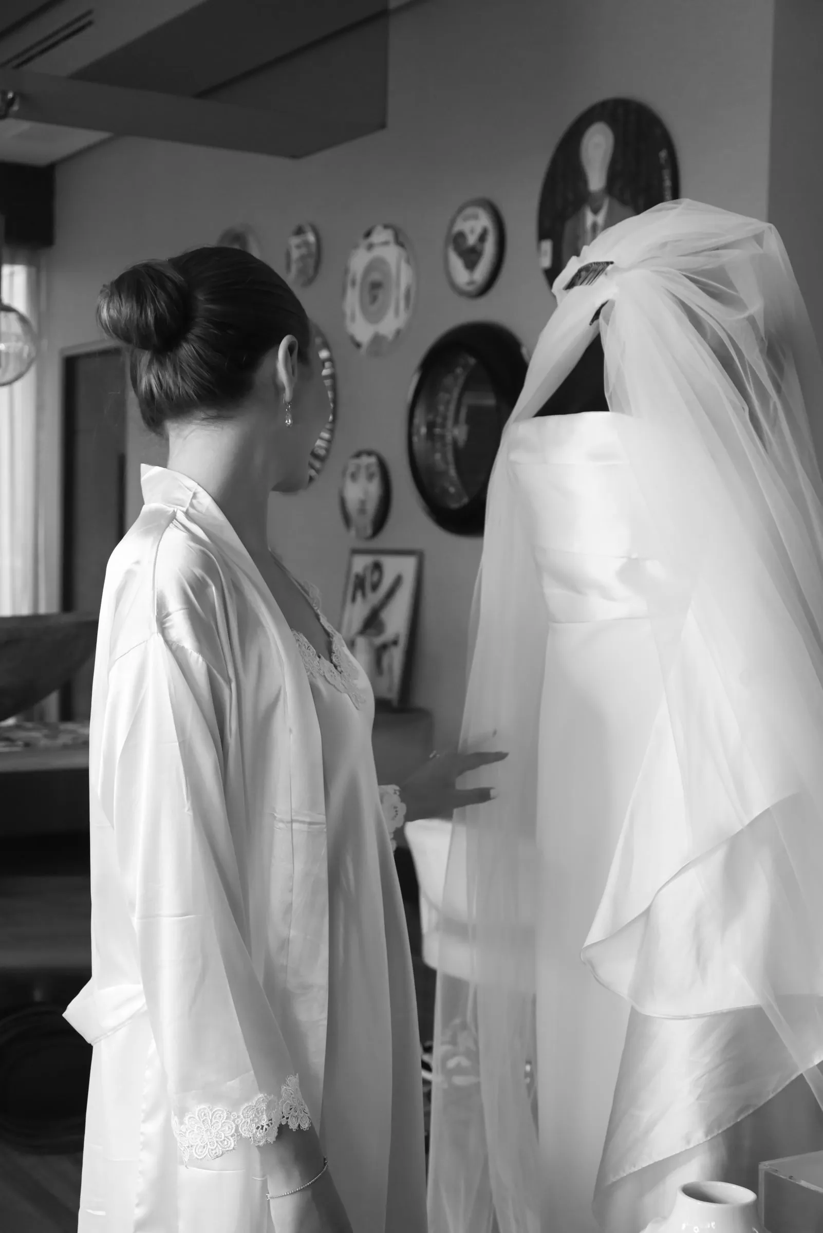 Novia de espaldas frente al maniquí con el vestido colgado