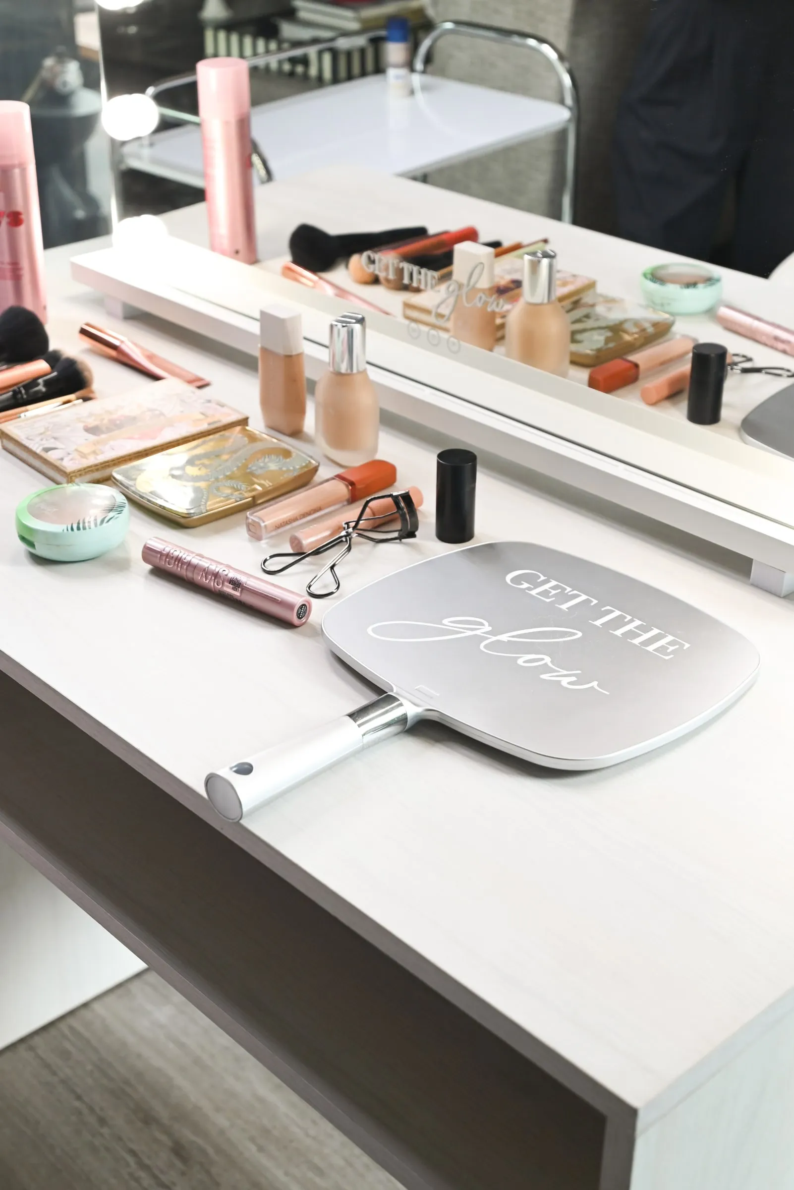 Productos de maquillaje y el espejo de mano sobre la mesa del espejo